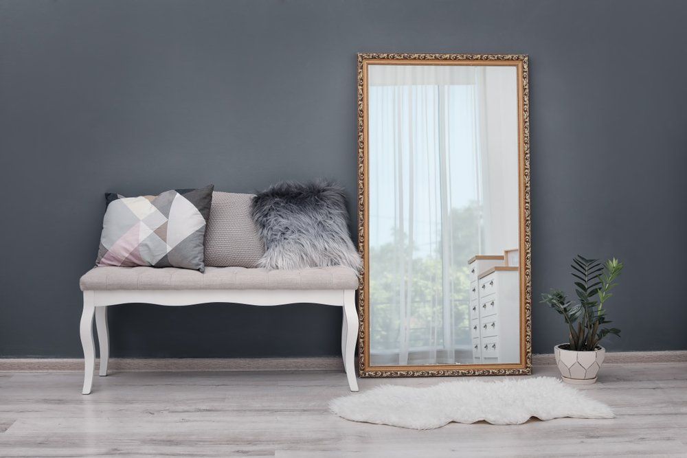 A living room with a bench and a large mirror.