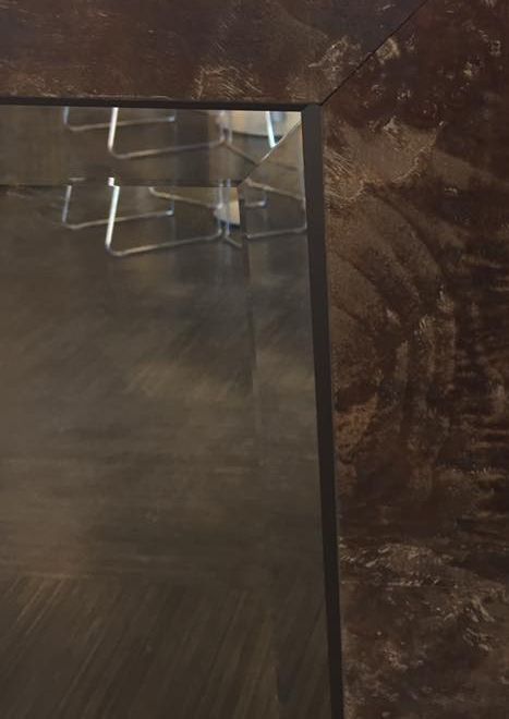 A mirror with a wooden frame is sitting on a wooden floor.