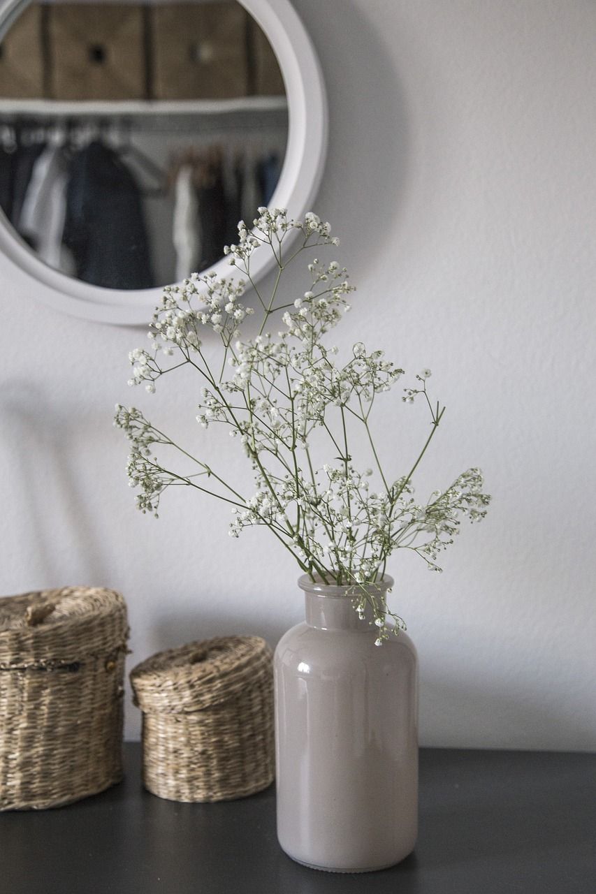 a vase filled with white flowers is on a table in front of a mirror .