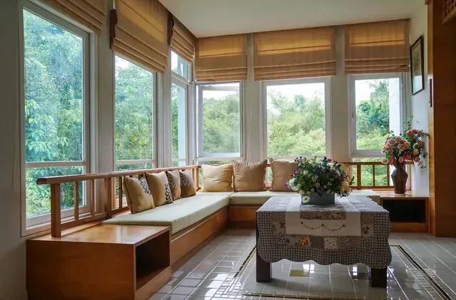 A living room with a couch , coffee table , and lots of windows.