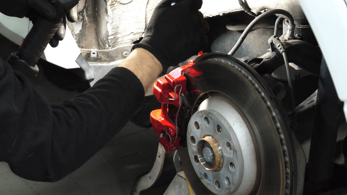 A mechanic with black gloves changing brake parts