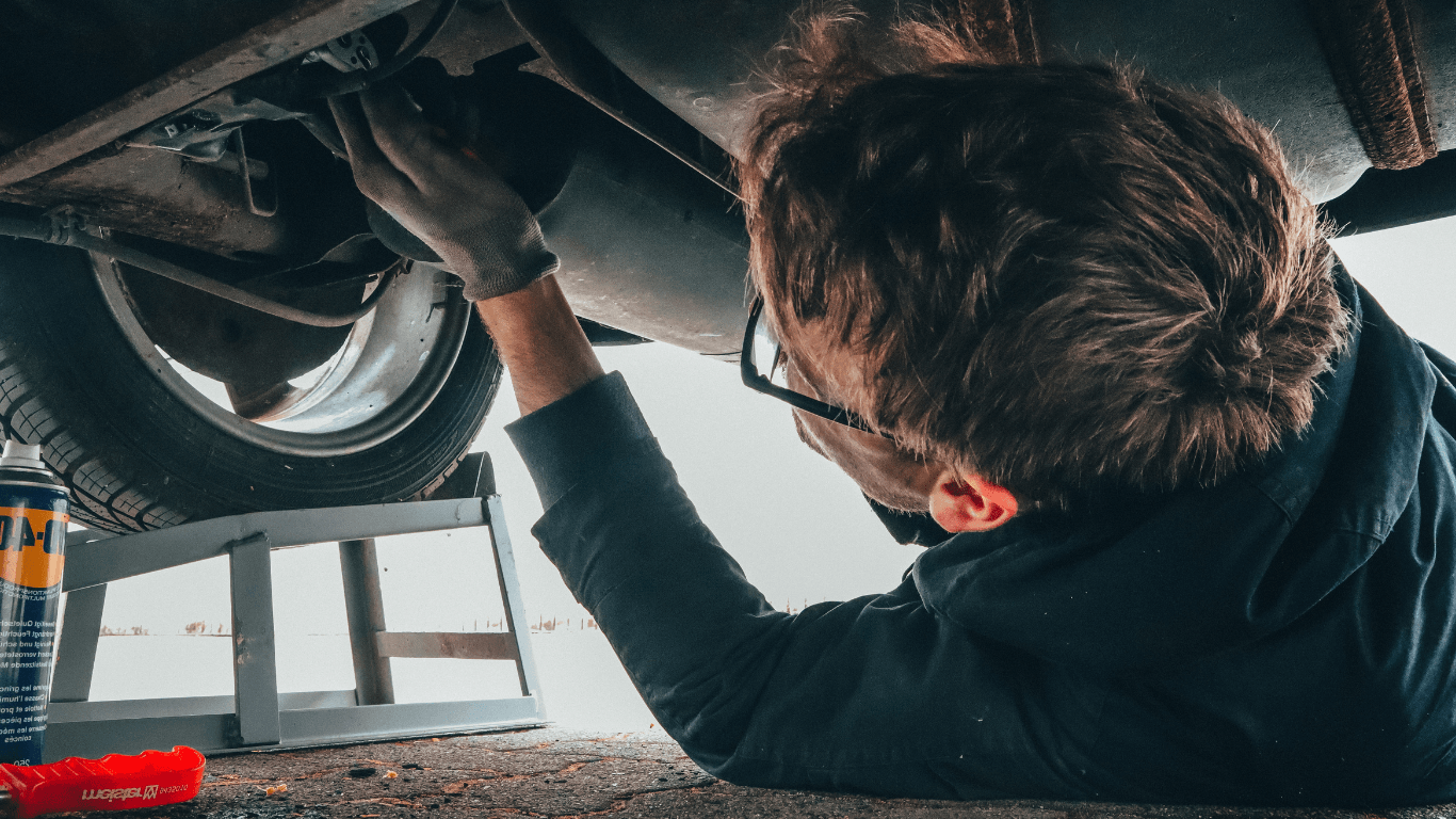 A mechanic under a car doing a repair