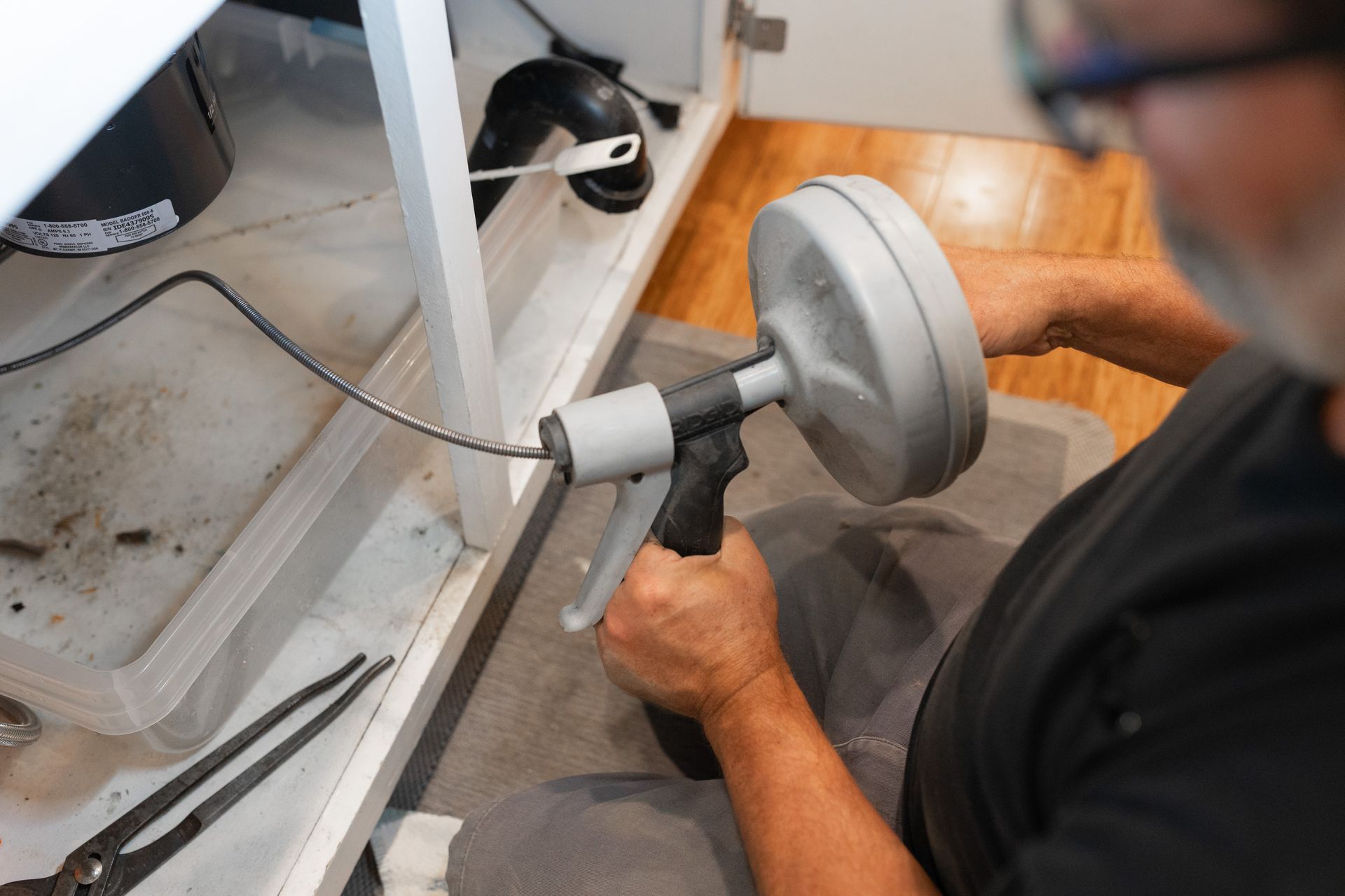 A plumber uses a drain snake to clear clogs and restore proper drain flow.