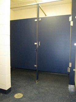 Public restroom stalls with blue doors and dark flooring, viewed from outside the stall area