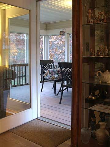 Sunroom with sliding glass doors, wicker chairs, and a glass display cabinet by the entryway