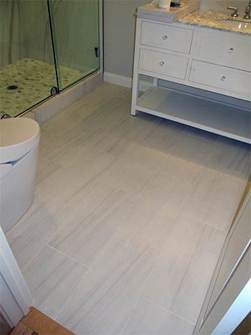 Modern bathroom with light wood floor, white vanity, toilet, and glass shower enclosure