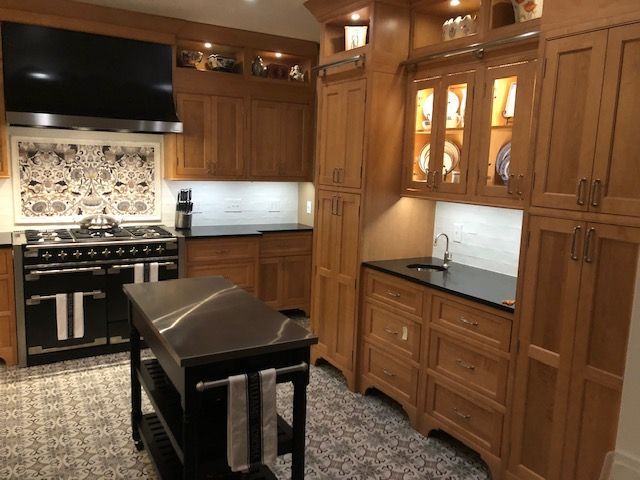 Warm wood kitchen with black stove, patterned backsplash, island, and built-in cabinets