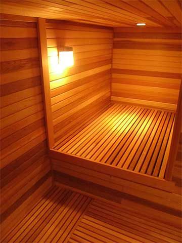 Wood-paneled sauna interior with warm lighting and slatted benches