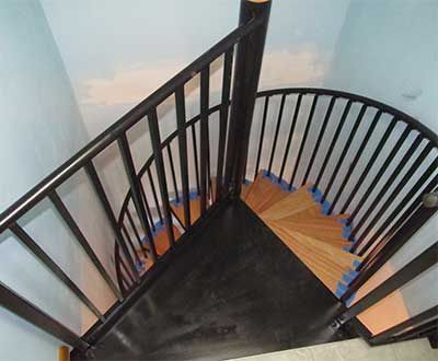 Black spiral staircase with metal railing and wooden steps