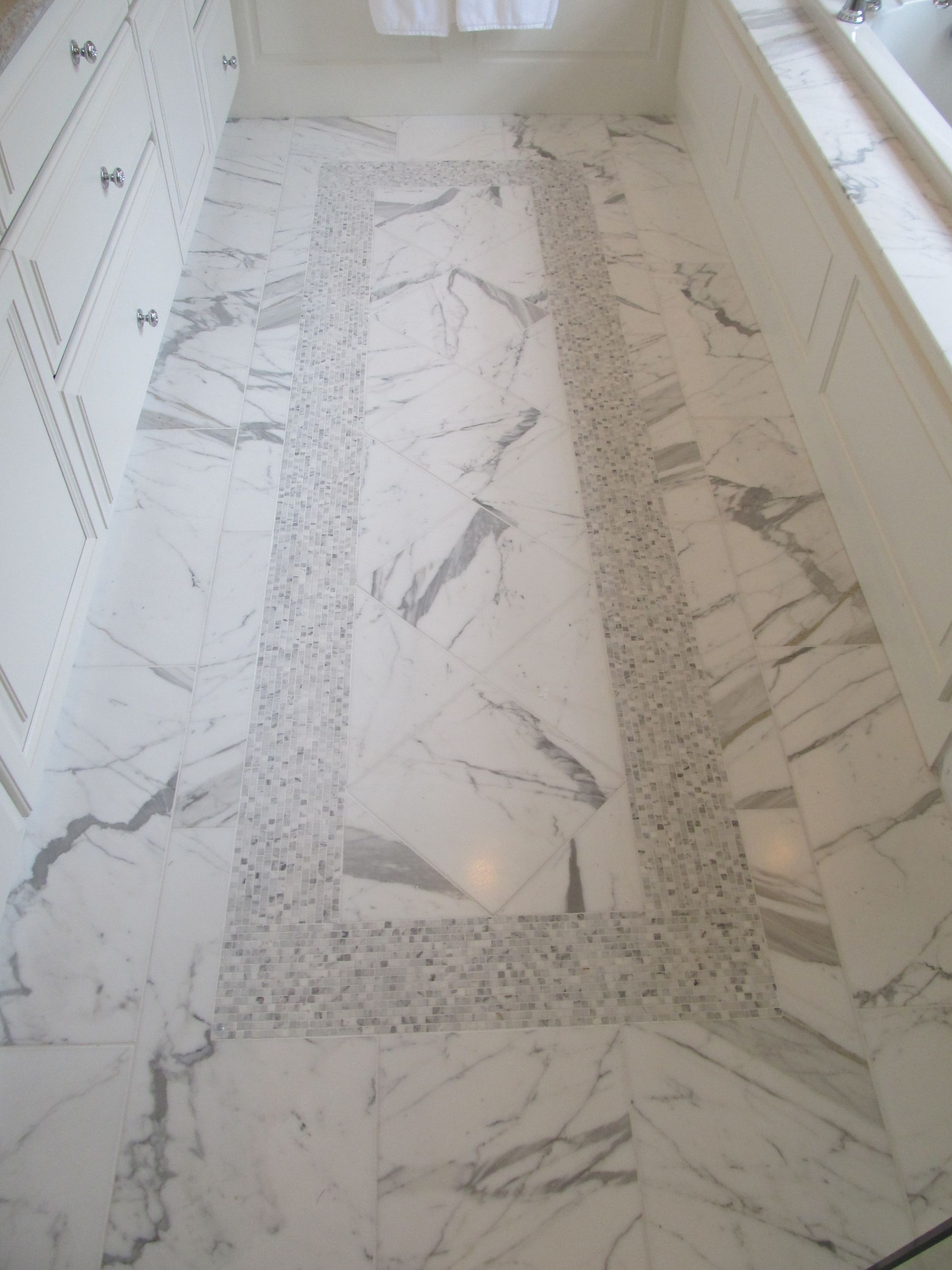 Marble-tiled bathroom floor with a partial shower or tub surround and wall tiles along the sides