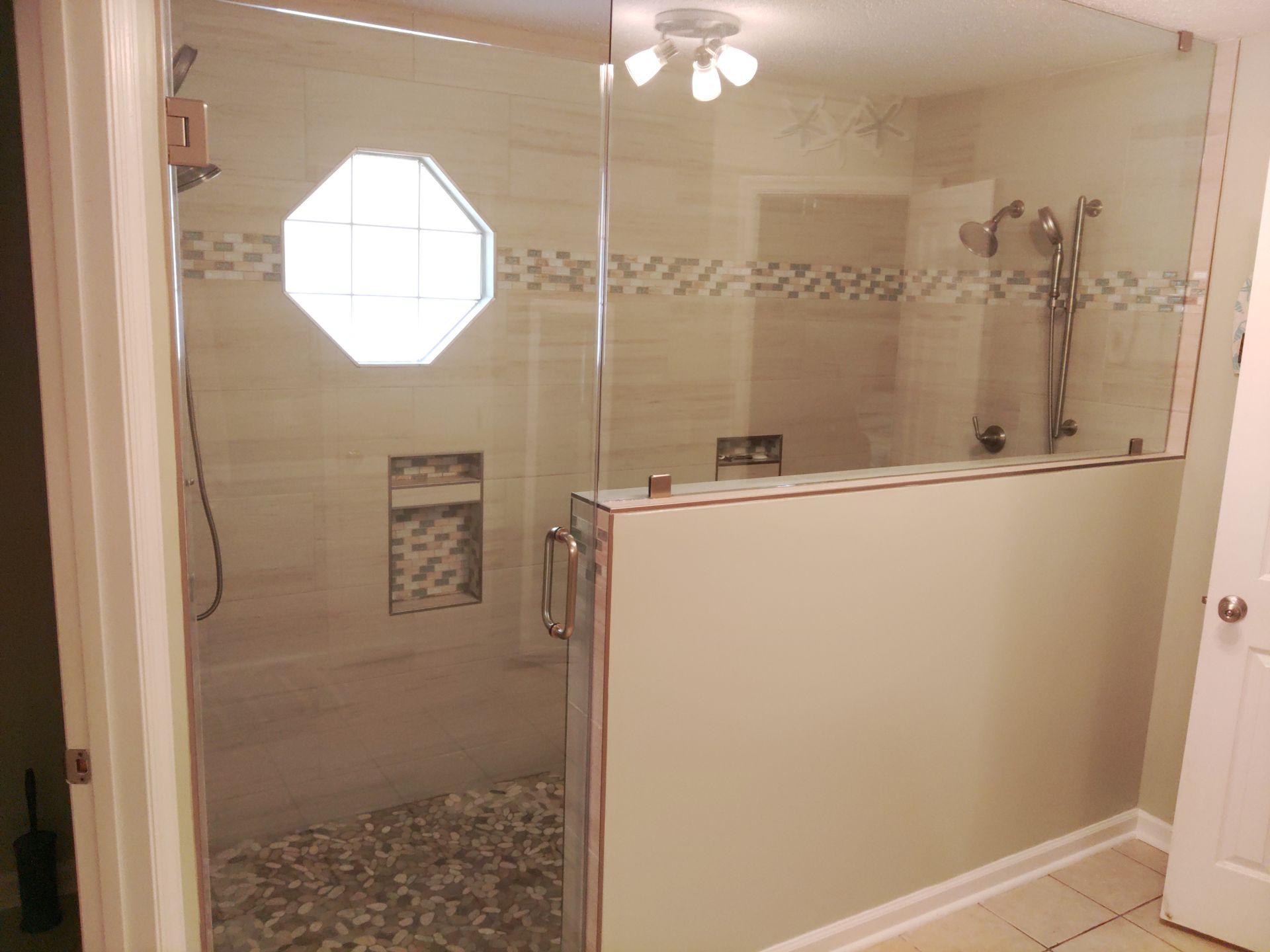 Bathroom with walk-in tiled shower, glass door, and octagonal window.