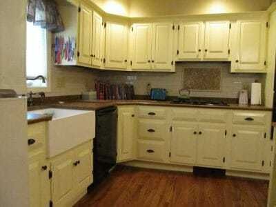 White kitchen with cream cabinets, dark countertops, sink, and wood floor.