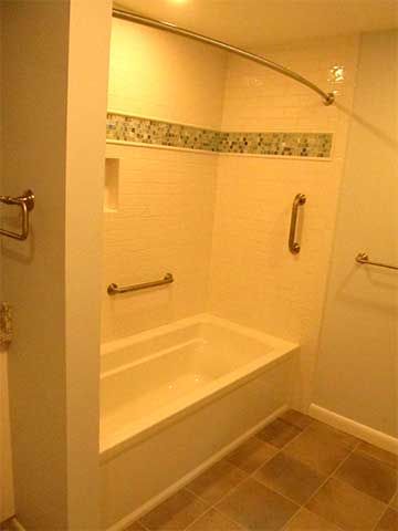 Small tiled shower-tub combo with beige walls, grab bars, and a curved shower rod