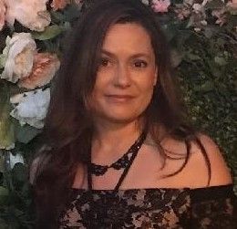 Woman in a black lace dress posing before a floral backdrop