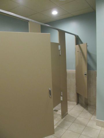 Public restroom stalls with beige partitions and tiled floor