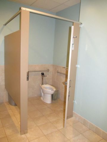 Accessible restroom stall with toilet and blue walls in a tiled bathroom