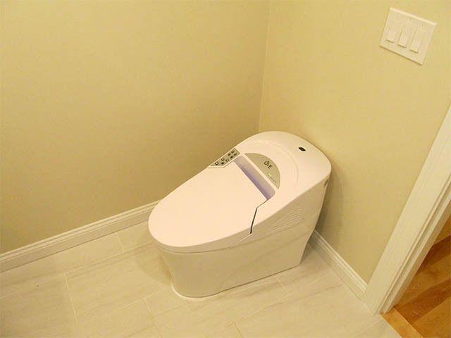 Modern white toilet in a small beige bathroom corner with a closed lid.