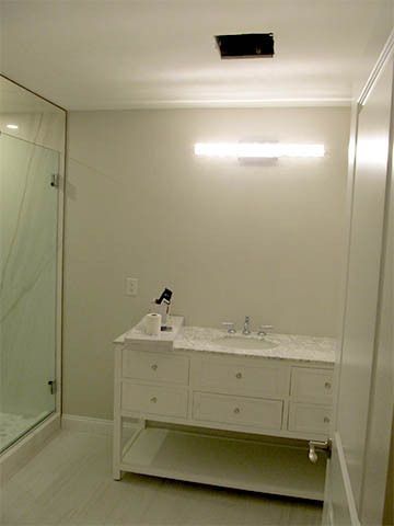 Bathroom with white vanity, wall mirror, and bright vanity light over marble countertop.
