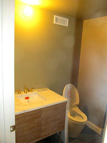 Small bathroom with sink vanity, toilet, and yellow wall light.