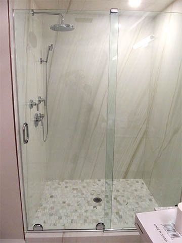 Glass walk-in shower with white tile floor and chrome fixtures