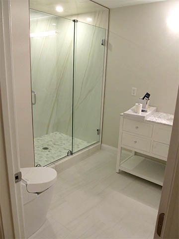 Modern bathroom with glass shower, white vanity, and wall-mounted toilet.