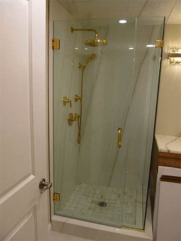 Small bathroom shower stall with glass doors and gold fixtures