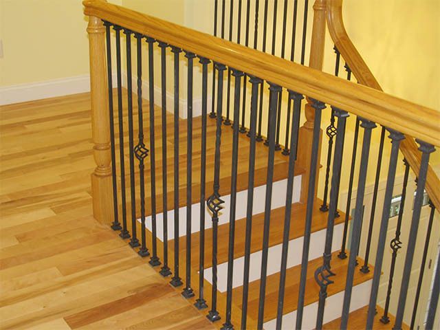 Wooden staircase with dark metal balusters and railing in a bright home interior