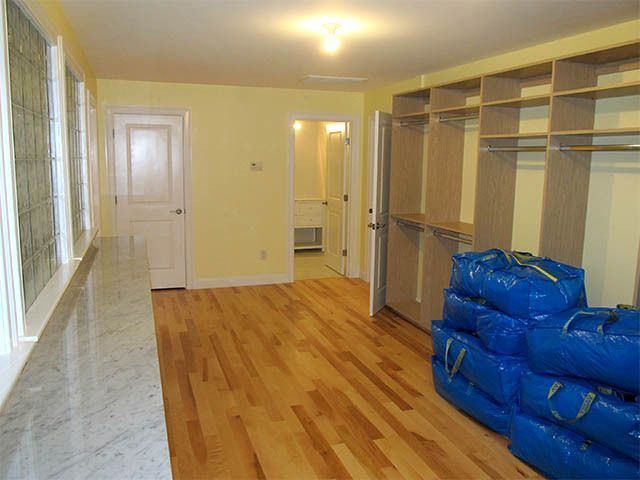 Empty room with hardwood floor, shelves, and stacked blue bags by a doorway