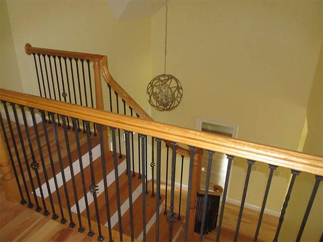 Staircase with wooden handrail and black balusters in a beige interior hall