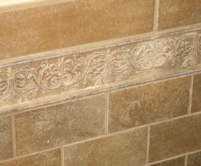 Tan decorative tan stone tile wall with a floral relief border band