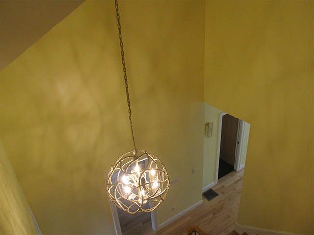 Yellow stairwell with a hanging spherical pendant light and a doorway on the right