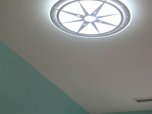 Ceiling with glowing star-shaped light fixture and teal wall corner