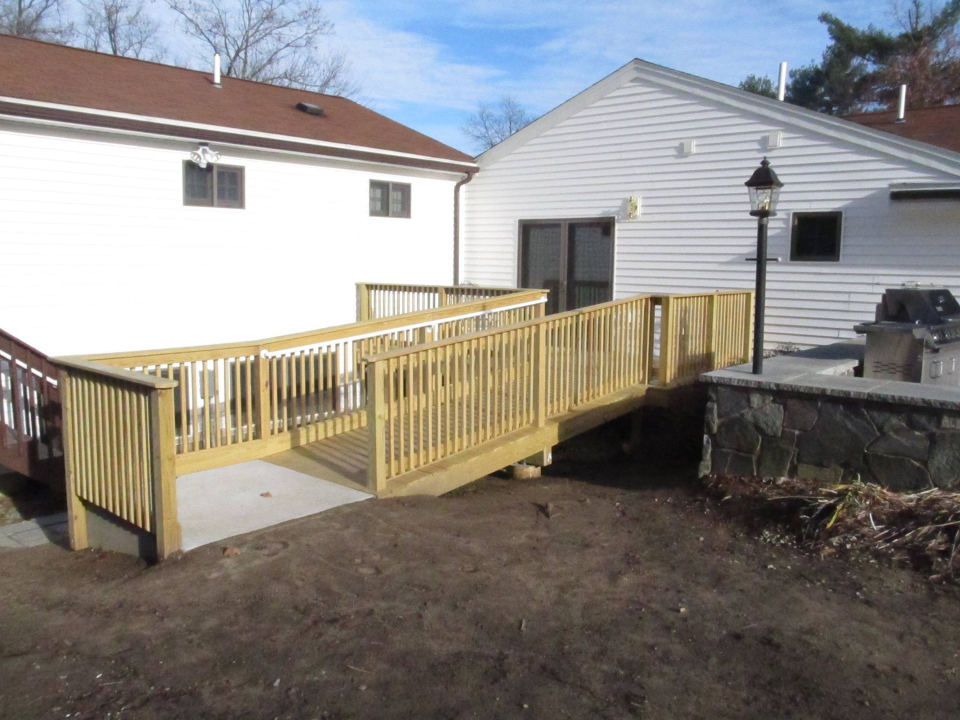 Yellow wheelchair ramp leading to a house entrance beside a white building