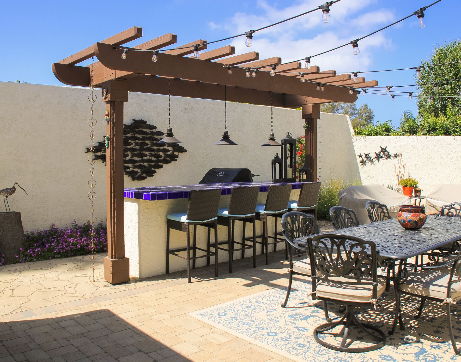 Patio bar with pergola, stools, and dining table in a sunny backyard