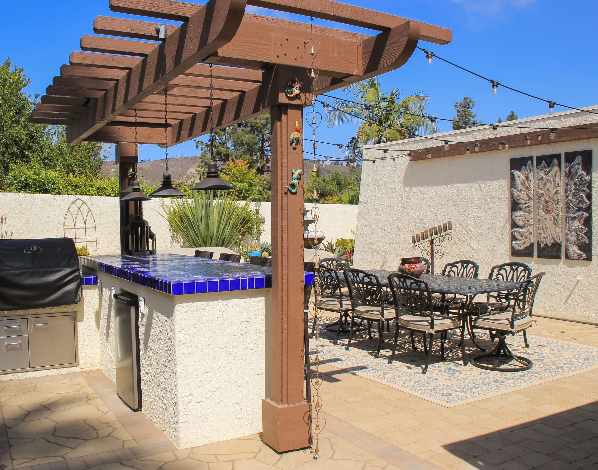 Backyard patio with pergola, blue-tiled spa, and outdoor dining table and chairs