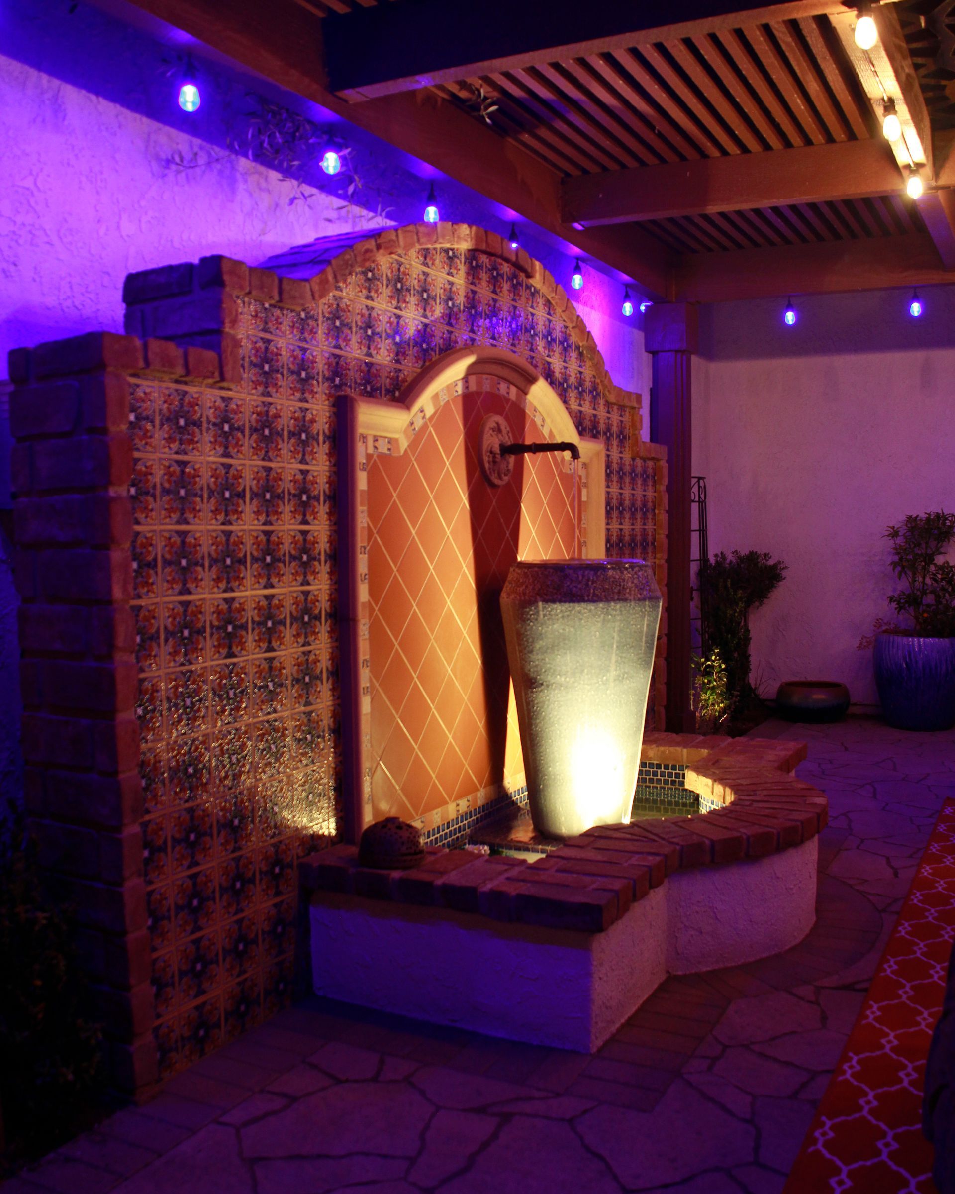 Indoor decorative fountain glowing under purple lights in a tiled courtyard