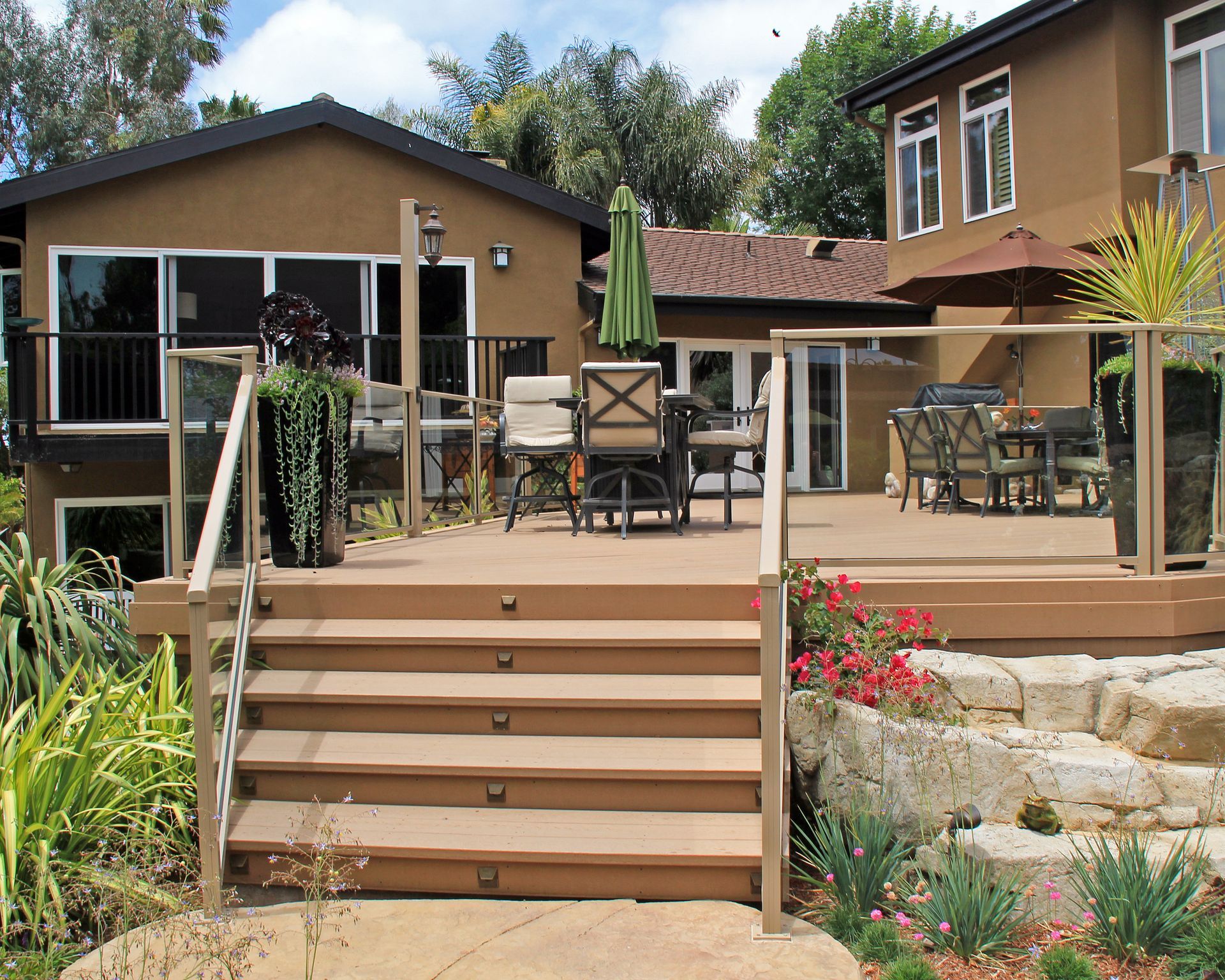 Backyard deck with stairs, outdoor seating, and a landscaped garden by a house