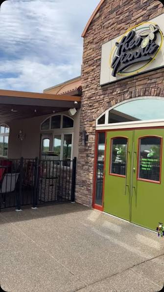The entrance to Theo Yianni’s on American Way in Weirton, with green double doors and the lit restaurant sign