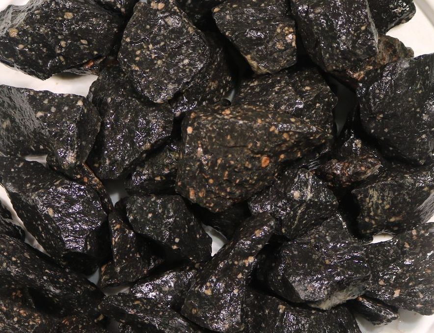 A pile of black rocks on a white surface