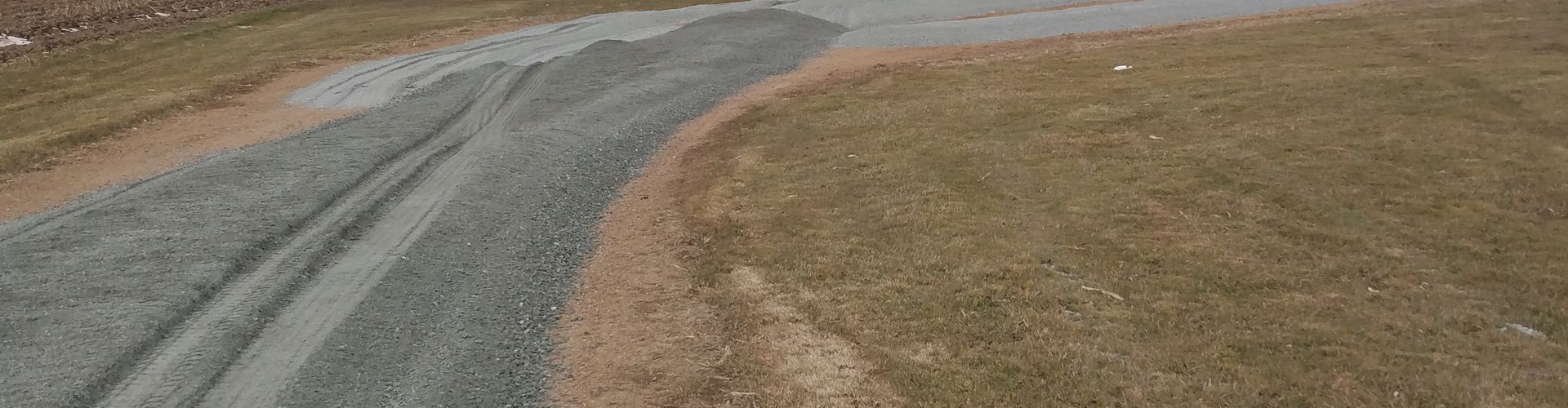 An aerial view of a road going through a grassy field.