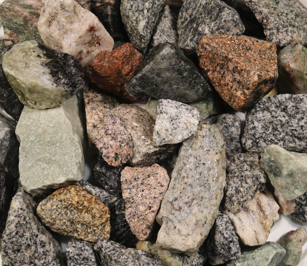 A pile of rocks of different sizes and colors on a white surface.