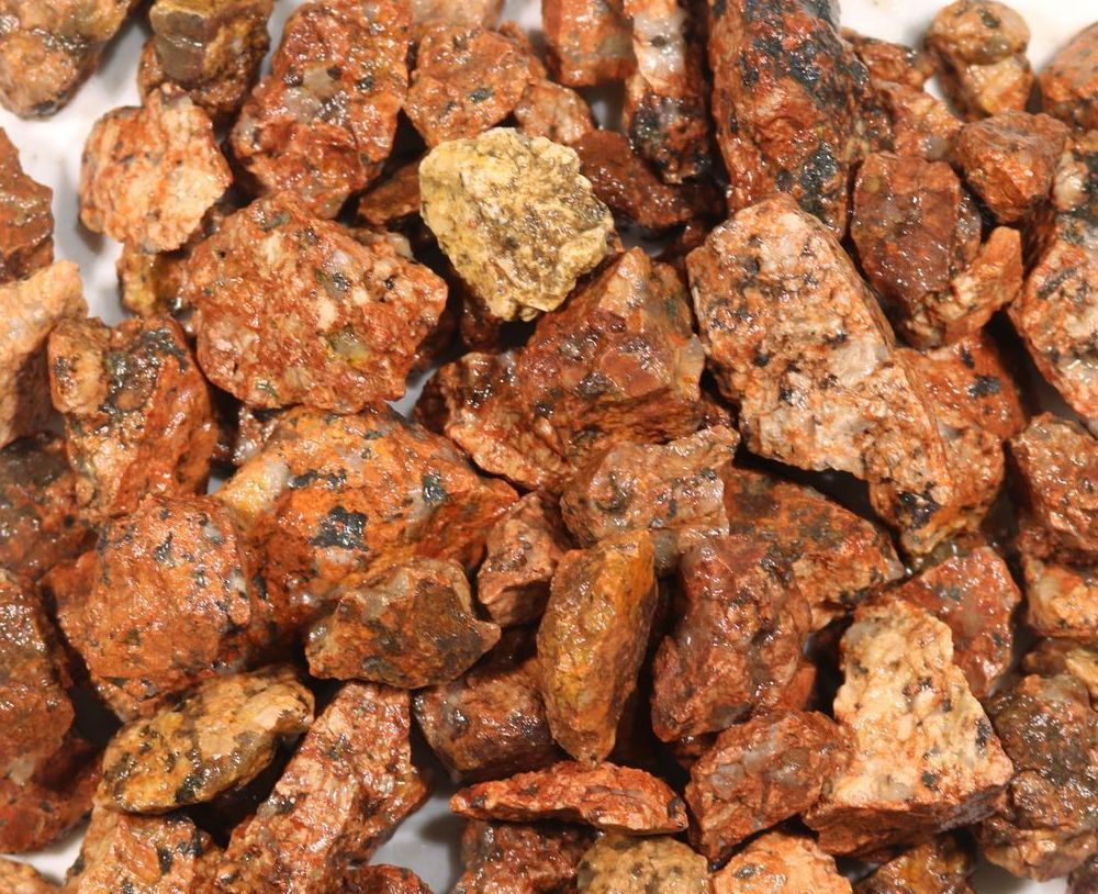 A pile of red rocks on a white surface.