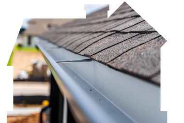 A close-up view of a clean gray metal rain gutter installed along the edge of a shingled roof.
