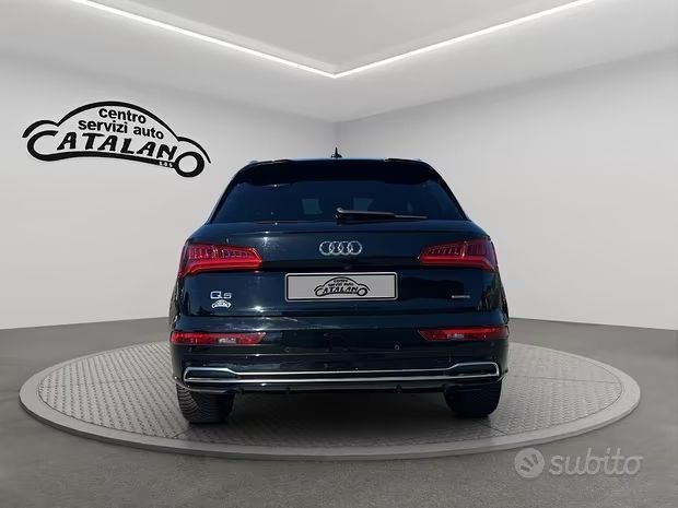 Vista posteriore di un SUV Audi blu scuro su una piattaforma girevole in una sala espositiva, con l'insegna Conti Catalano.