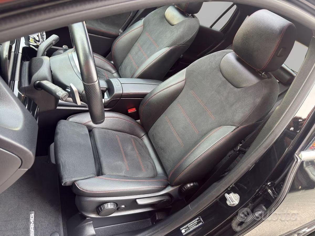 Sedili anteriori di un'auto compatta con rivestimento grigio scuro e volante a vista.
