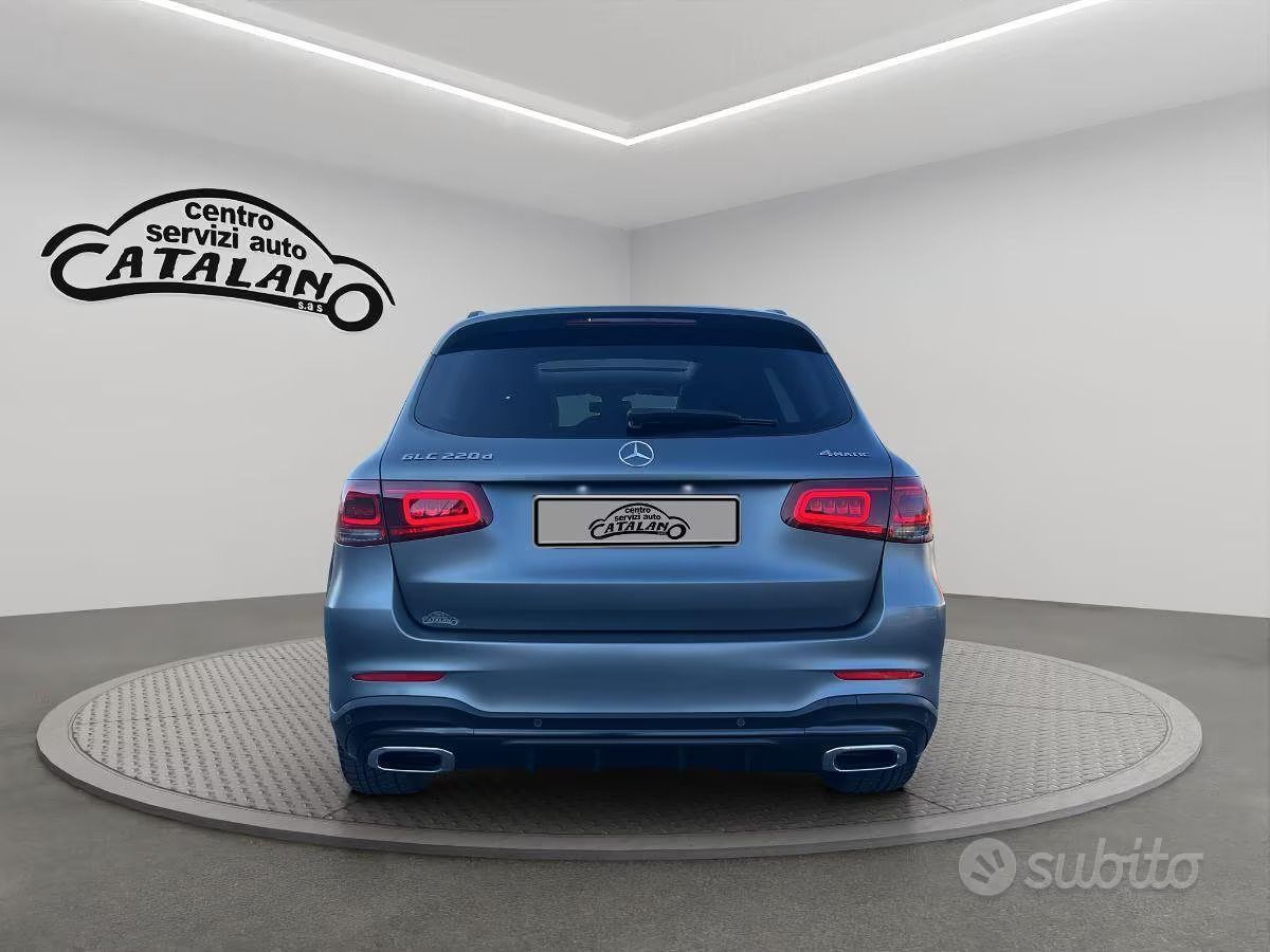 Vista posteriore di un SUV blu su una piattaforma espositiva girevole in uno showroom.