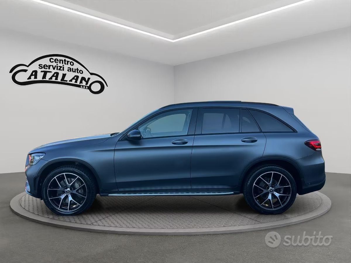 SUV blu visto di profilo su uno sfondo da studio con una piattaforma circolare.