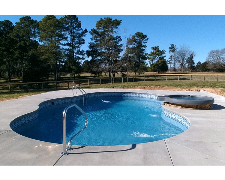 Swimming pool with clear blue water and attached hot tub on a sunny day.
