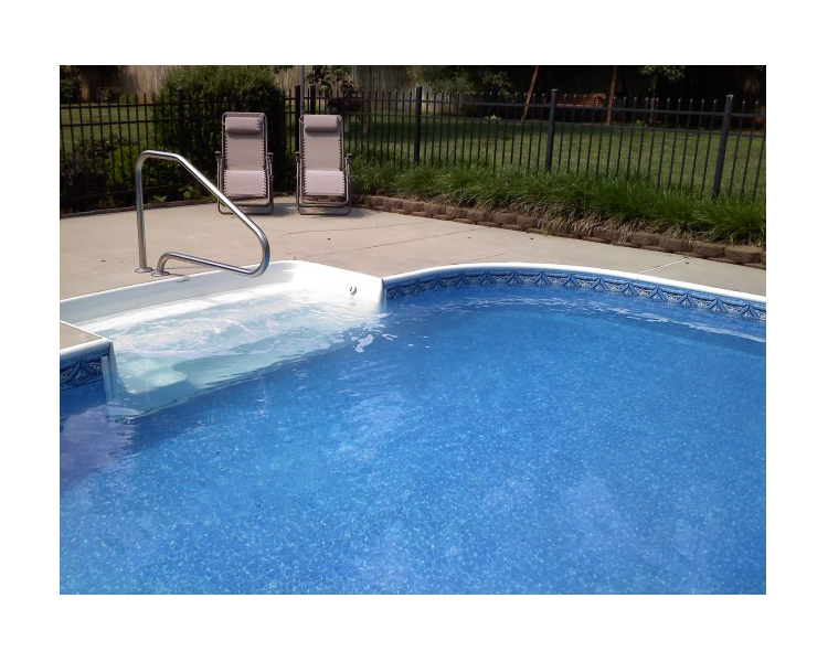 Swimming pool with steps, handrail, and two lounge chairs on the patio.
