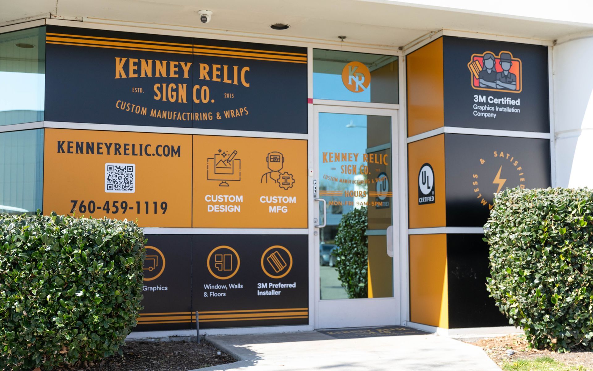 Kenney Relic Sign Co. storefront with orange-and-black signage and glass entrance.